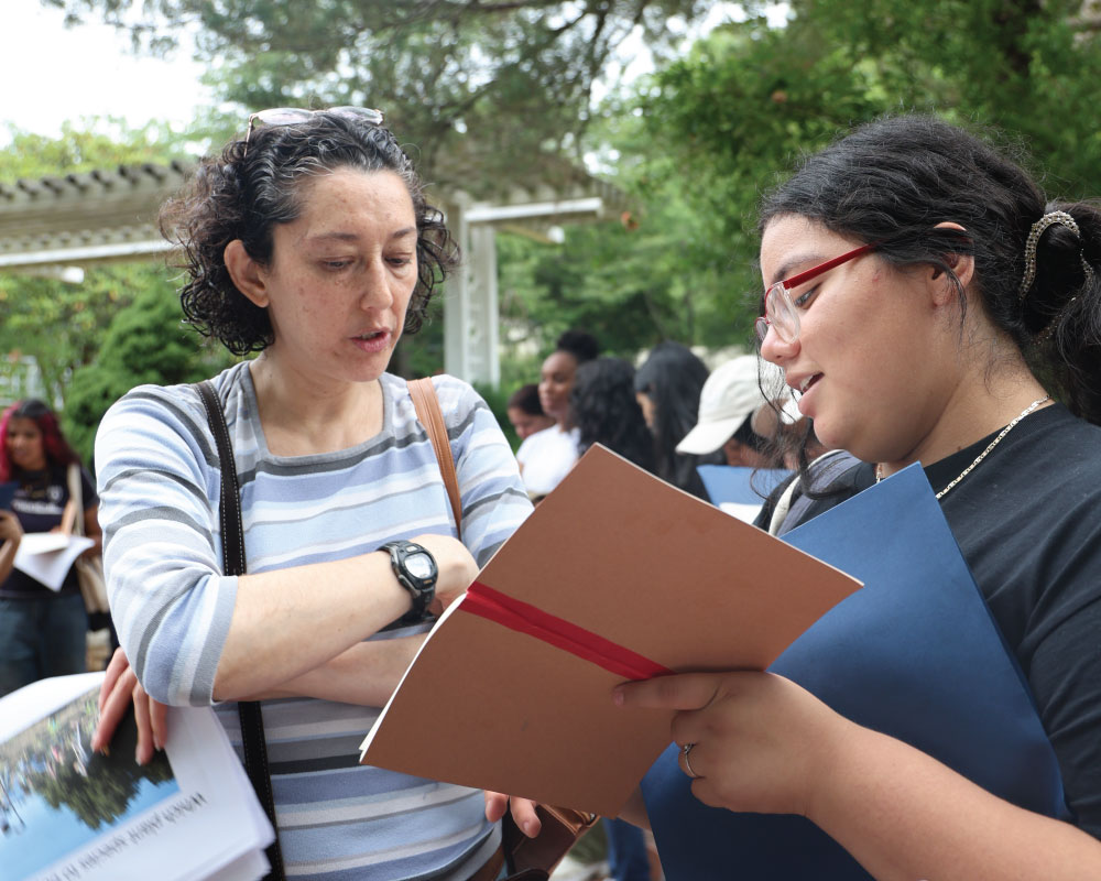 a student and professor talking and looking at a notebook